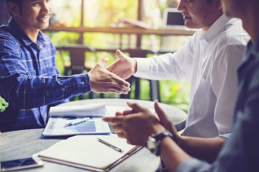 Businessmen negotiate in a coffee shop. Hold hands and greet before the business talks comfortably.