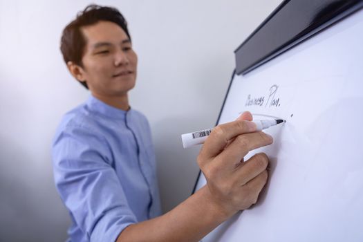 Young businessman writing on white board in conference room to planning of the agency. Business meeting presentation concept
