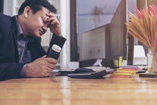 Stressed businessman having severe headache, holding painkiller remedy pill. Stress job