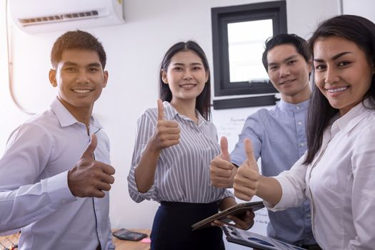 Group of business partners showing thumbs up while sitting at workplace in office. Hands of businessman holds many thumbs up, Excellent work, congratulates and businessman success concept.