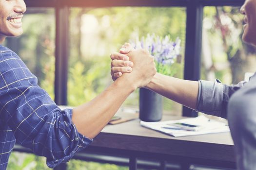 Businessmen negotiate in a coffee shop. Hold hands and greet before the business talks comfortably.