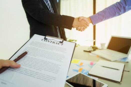 Two businessmen are shaking hands after agreeing to a contract.