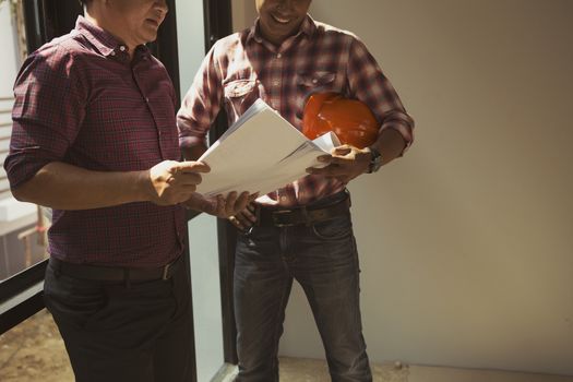 Two engineers are working on a blueprint. With work space