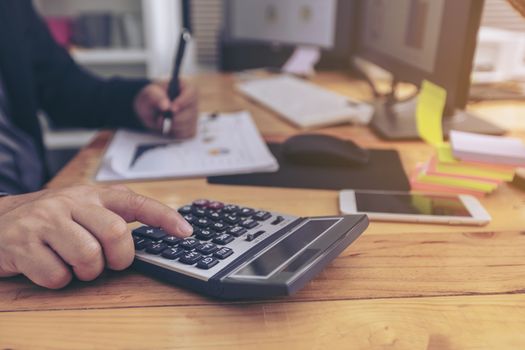 closeup of a young man checking accounts with a calculator