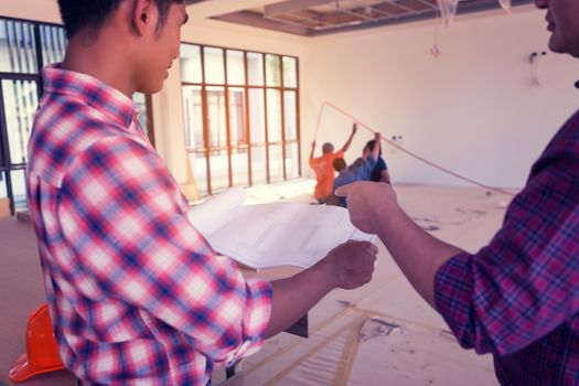 Two engineers are working on a blueprint. With work space