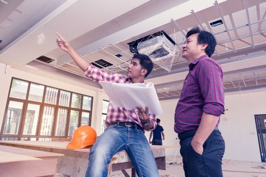 Two engineers are working on a blueprint. With work space