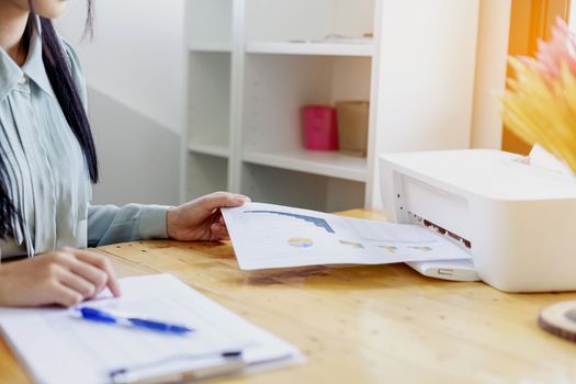 Beautiful young businesswoman doing some paperwork while sitting at office desk in front of computer.