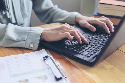 Beautiful young businesswoman doing some paperwork while sitting at office desk in front of computer.