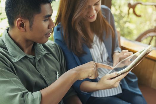 Couple using digital tablet together to choose something.