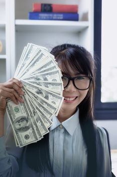 Successful business women are counting money and throwing a dollar at work happily.