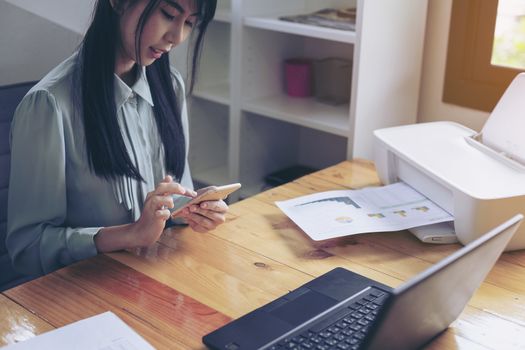 Beautiful young businesswoman doing some paperwork while sitting at office desk in front of computer.