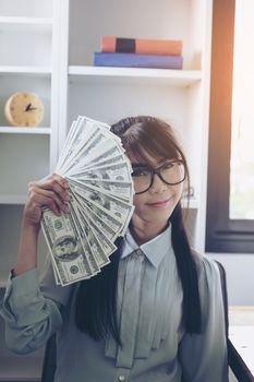 Successful business women are counting money and throwing a dollar at work happily.