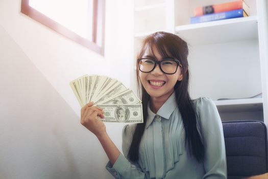 Successful business women are counting money and throwing a dollar at work happily.