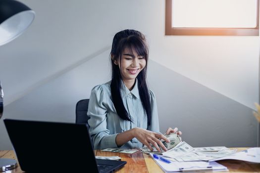 Successful business women are counting money and throwing a dollar at work happily.