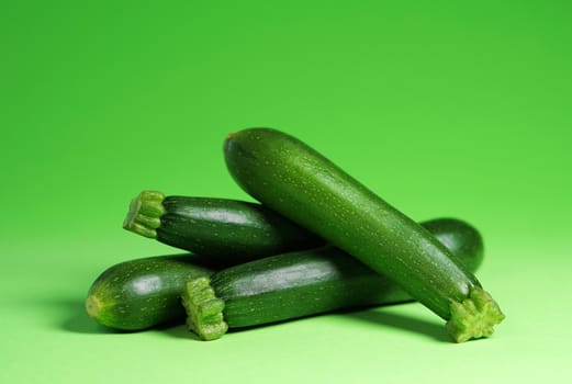 Zucchini vegetables portrait concept with four fresh organic baby zucchini close up view on green background with copy space.