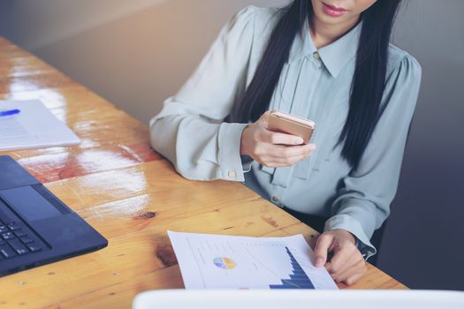 Beautiful young businesswoman doing some paperwork while sitting at office desk in front of computer.