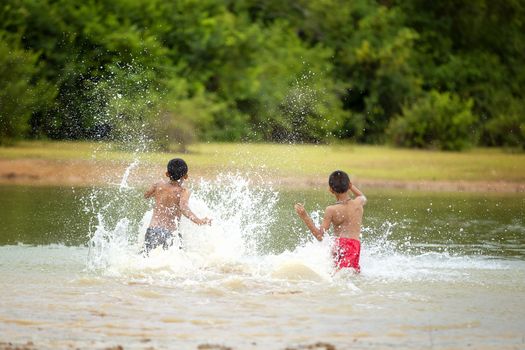 Asian children are playing in the river joyfully.