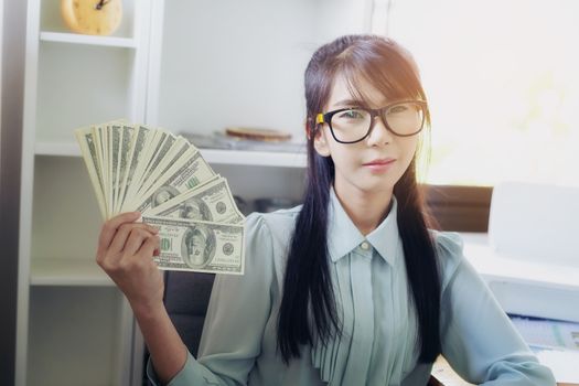 Successful business women are counting money and throwing a dollar at work happily.