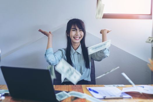 Successful business women are counting money and throwing a dollar at work happily.