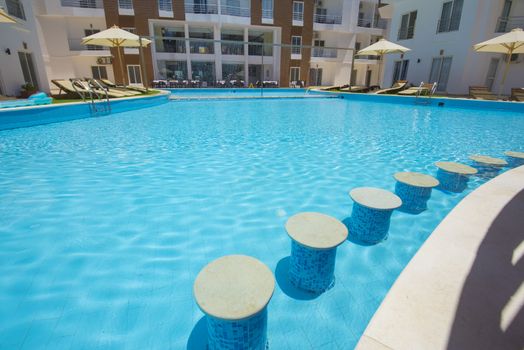 Large swimming pool with bar at a luxury tropical hotel apartment resort