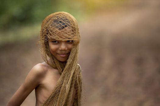 The image of a young man using a fishing net to cover his head and taking off his shirt. country young boy portrait in outdoors,Happy rural young boy smiling in field,portrait of a happy young asian young boy.