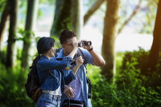 Young people are looking through binoculars with concentration while in the forest. Hiking concept, Travel concept.