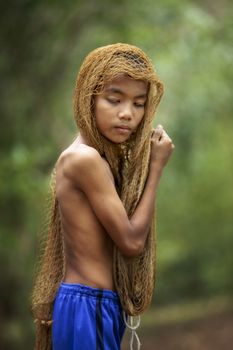 The image of a young man using a fishing net to cover his head and taking off his shirt. country young boy portrait in outdoors,Happy rural young boy smiling in field,portrait of a happy young asian young boy.