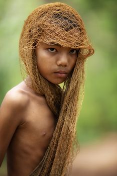 The image of a young man using a fishing net to cover his head and taking off his shirt. country young boy portrait in outdoors,Happy rural young boy smiling in field,portrait of a happy young asian young boy.