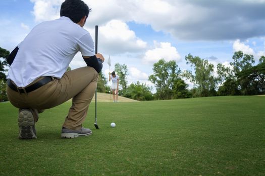 Golf player check line for putting golf ball on green grass. Golf player crouching and study the green before putting shot