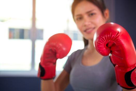 Woman with red boxing wraps and boxing gloves on hands boxing in ring. Active girl fight