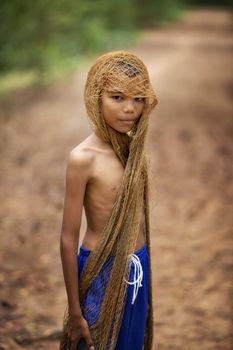 The image of a young man using a fishing net to cover his head and taking off his shirt. country young boy portrait in outdoors,Happy rural young boy smiling in field,portrait of a happy young asian young boy.