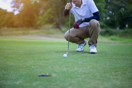 Golf player check line for putting golf ball on green grass. Golf player crouching and study the green before putting shot