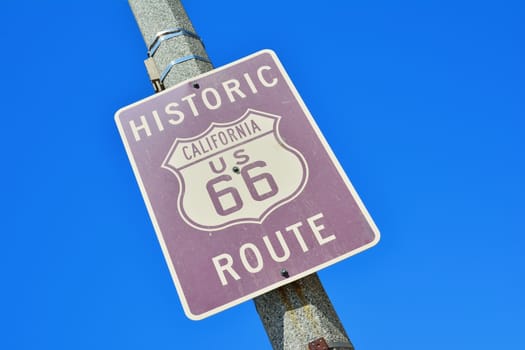 Historic California Route 66 road sign on a blue sky.