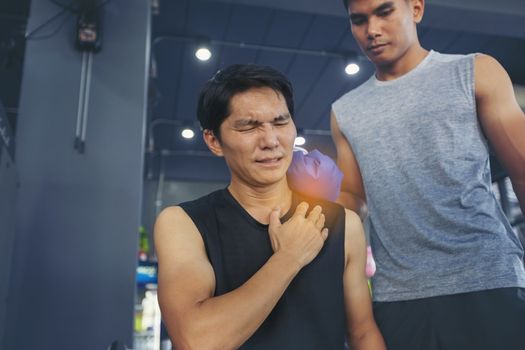 Handsome young man who is feeling pain from exercise and received an ice pack from his friend to relieve the pain