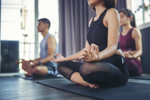 Beautiful woman practicing yoga position and has a close trainer in an indoor gym studio. Healthy and wellness lifestyle concept