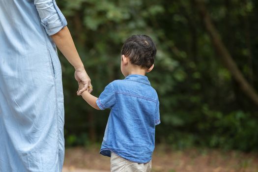 Happy mother and adorable little boy enjoying warm weather at beautiful park