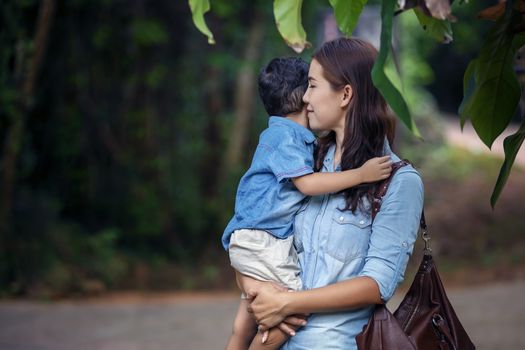 Happy mother and adorable little boy enjoying warm weather at beautiful park