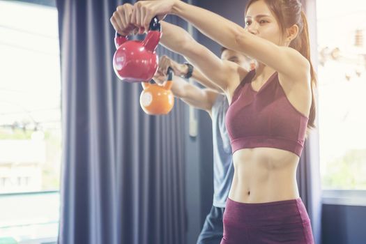 Beautiful woman practicing yoga position and has a close trainer in an indoor gym studio. Healthy and wellness lifestyle concept