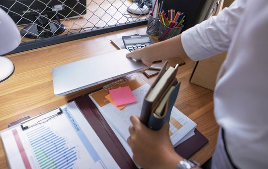 Upset female employee packing belongings in box, frustrated stressed girl getting fired from job ready to leave on last day at work. sad office worker desperate from work
