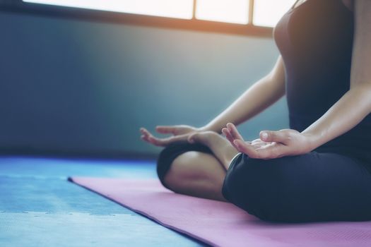 Beautiful woman practicing yoga position in an indoor gym studio. Healthy and wellness lifestyle concept