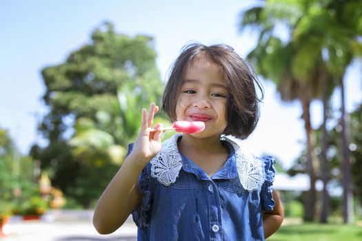 Cute little girl eating popsicle with sunset background