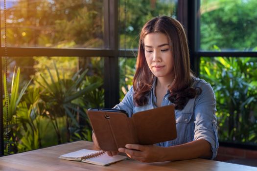 Beautiful Asian businesswoman who uses a tablet in the coffee shop to contact customers and check emails. Business concept