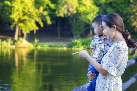 Mother and baby are happy, smiling, enjoying the warm and pure air in a beautiful garden.