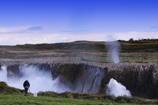 Bufones de Pria in the coast near a cliff in Asturias, Spain. A photographer takes pictures of the scene.