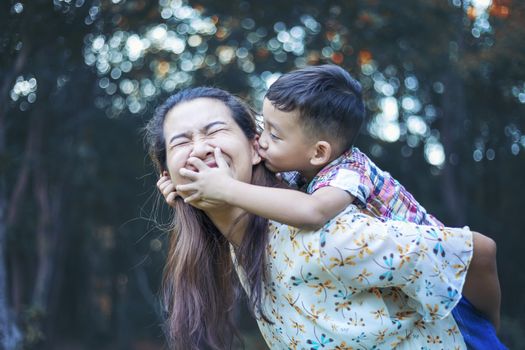 Mother and baby are happy, smiling, enjoying the warm and pure air in a beautiful garden.