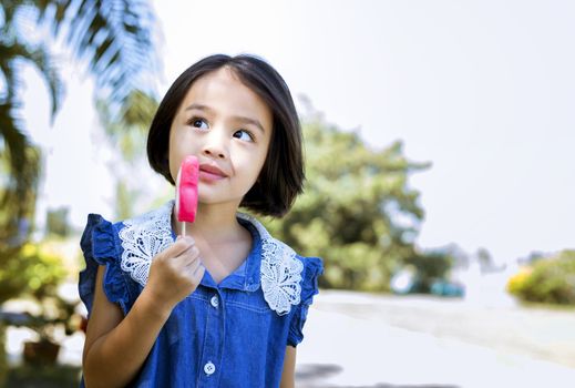 Cute little girl eating popsicle with sunset background