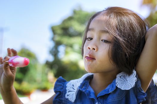 Cute little girl eating popsicle with sunset background