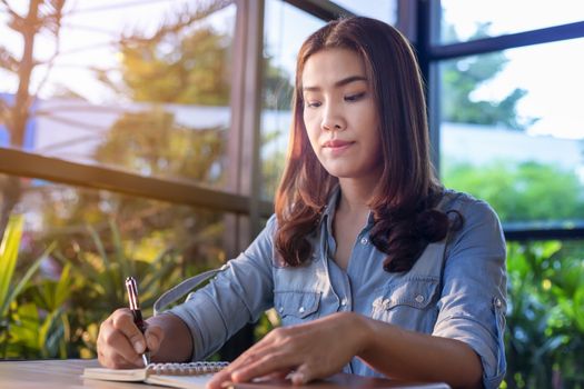 Beautiful Asian businesswoman who uses a tablet in the coffee shop to contact customers and check emails. Business concept