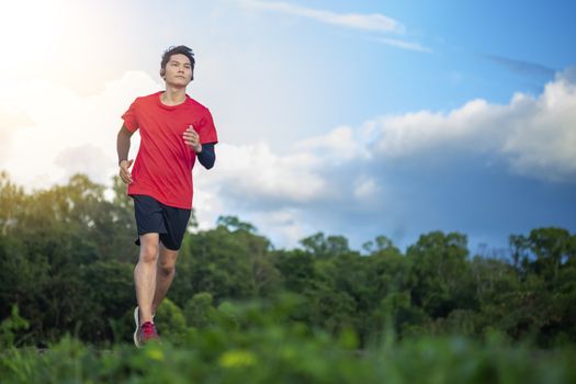 Handsome young man runs for good health on a rural road that is full of forests and beautiful nature.