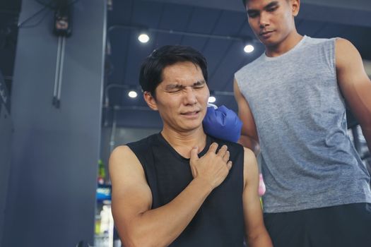 Handsome young man who is feeling pain from exercise and received an ice pack from his friend to relieve the pain